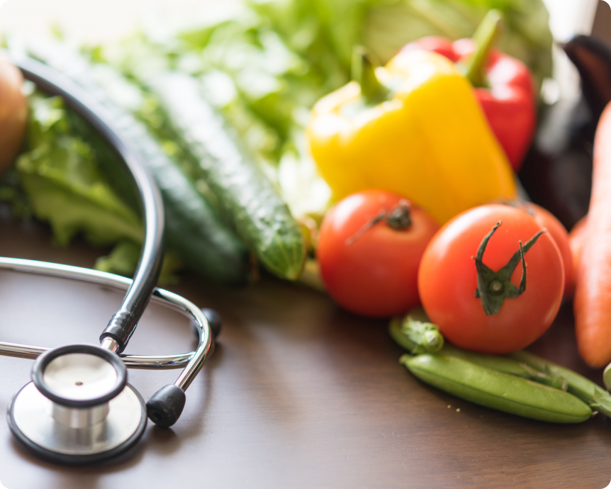 野菜と聴診器が置かれた写真。栄養と健康をイメージした構図