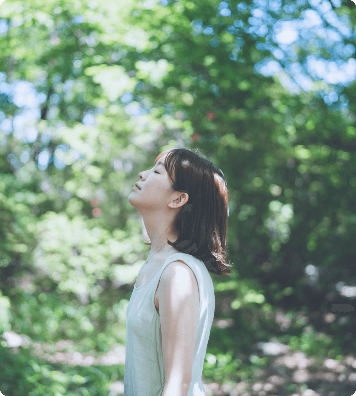 森の中で目を閉じて深呼吸する女性