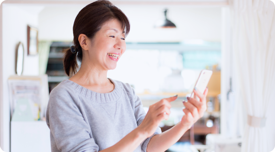 スマートフォンを手に笑顔を見せる女性。栄養カウンセラーとして感謝されながら働くイメージ